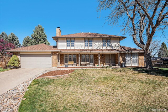 traditional-style home featuring a front lawn, driveway, a chimney, brick siding, and an attached garage