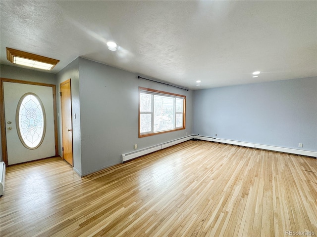 foyer featuring light wood-style flooring, a textured ceiling, and a baseboard radiator