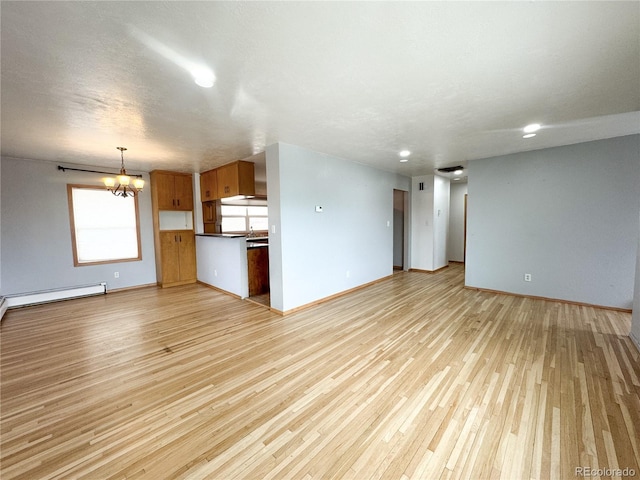 unfurnished living room with a baseboard heating unit, an inviting chandelier, baseboards, and light wood-type flooring