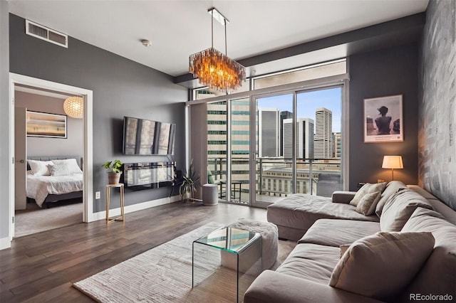 living area featuring wood finished floors, visible vents, baseboards, and an inviting chandelier