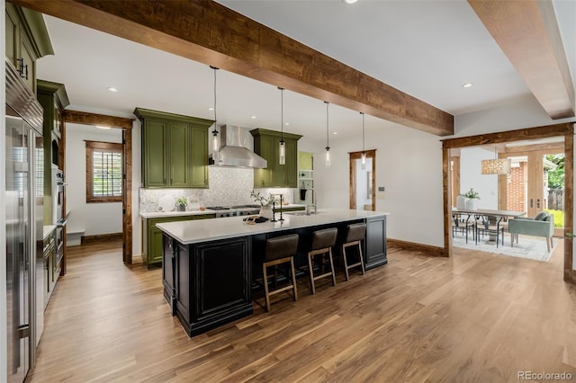 1332 S Lafayette St, Denver, CO 80210 - kitchen featuring green cabinetry, wall chimney exhaust hood, baseboards, light countertops, and beam ceiling
