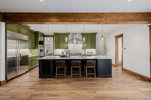 1332 S Lafayette St, Denver, CO 80210 - kitchen featuring green cabinets, stainless steel appliances, wall chimney exhaust hood, light wood-style floors, and recessed lighting