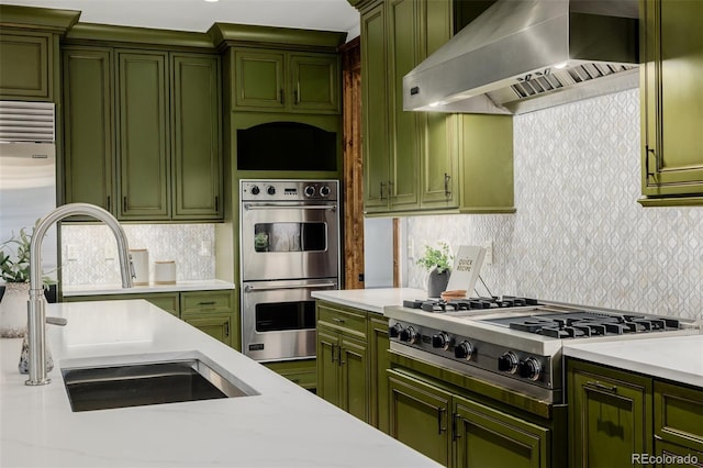 1332 S Lafayette St, Denver, CO 80210 - kitchen featuring green cabinets, wall chimney exhaust hood, stainless steel appliances, a sink, and light countertops