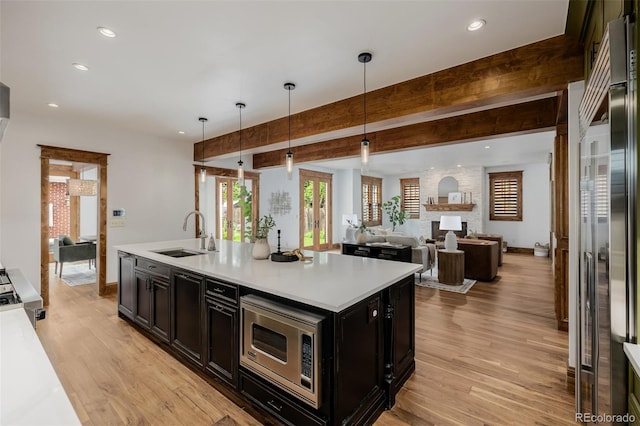 1332 S Lafayette St, Denver, CO 80210 - kitchen with a sink, stainless steel microwave, light wood-style floors, dark cabinets, and recessed lighting
