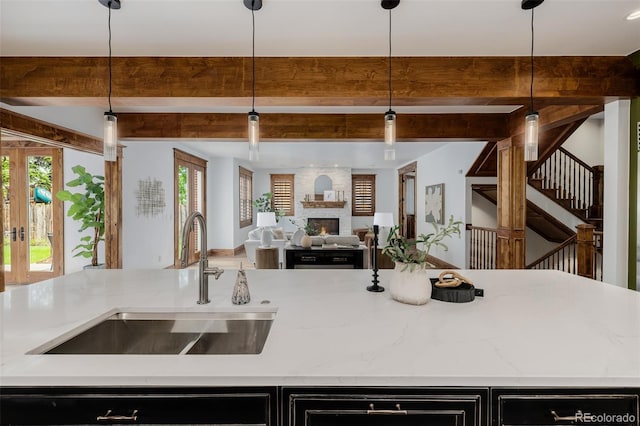 1332 S Lafayette St, Denver, CO 80210 - kitchen with open floor plan, a large fireplace, beamed ceiling, light stone countertops, and decorative light fixtures