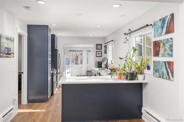 kitchen featuring sink, light hardwood / wood-style floors, a baseboard radiator, and kitchen peninsula