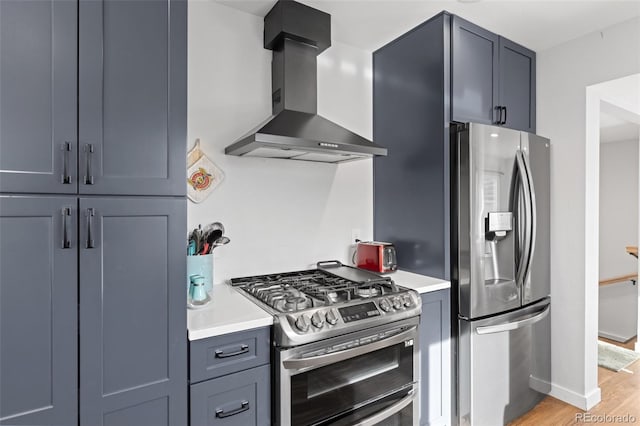 kitchen with appliances with stainless steel finishes, light hardwood / wood-style floors, and wall chimney range hood