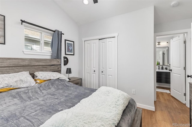 bedroom featuring vaulted ceiling, ensuite bath, a closet, light hardwood / wood-style floors, and ceiling fan