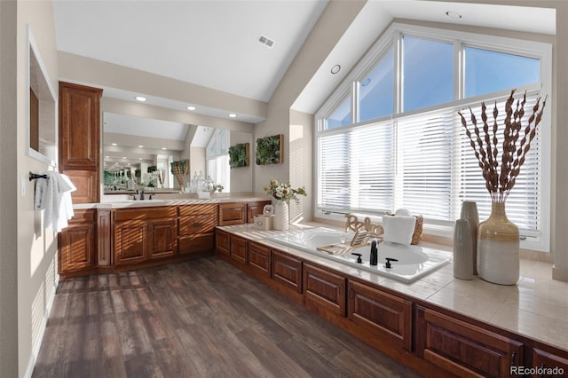 bathroom with vaulted ceiling, hardwood / wood-style floors, vanity, and a bathtub