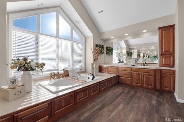 bathroom with lofted ceiling, vanity, hardwood / wood-style flooring, and a bathing tub