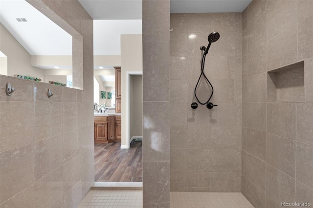 bathroom with tiled shower and vanity