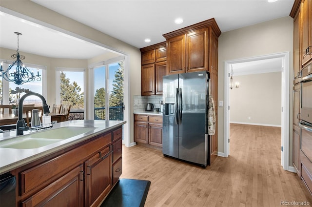 kitchen featuring appliances with stainless steel finishes, decorative light fixtures, sink, a notable chandelier, and light hardwood / wood-style floors