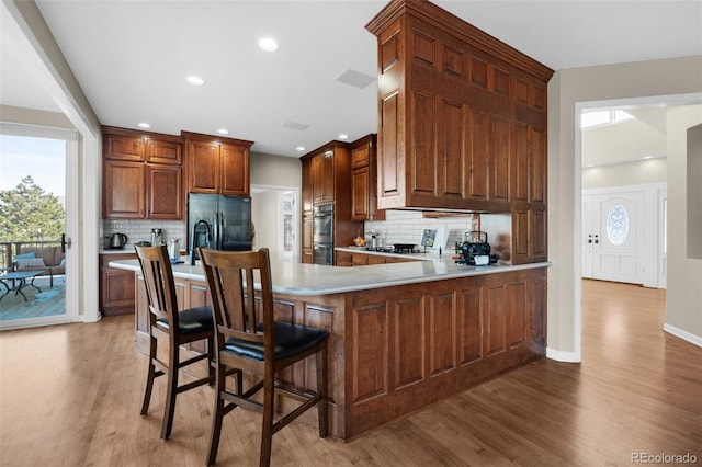 kitchen featuring stainless steel appliances, tasteful backsplash, a breakfast bar area, and light hardwood / wood-style flooring