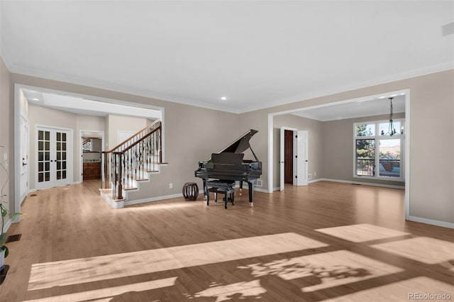 foyer featuring crown molding, light hardwood / wood-style flooring, french doors, and a chandelier