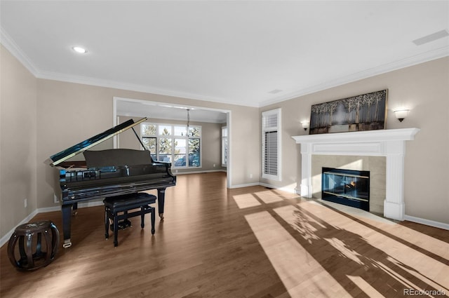 interior space featuring a notable chandelier, wood-type flooring, ornamental molding, and a tile fireplace