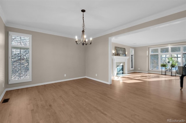 unfurnished living room featuring hardwood / wood-style flooring, ornamental molding, and an inviting chandelier