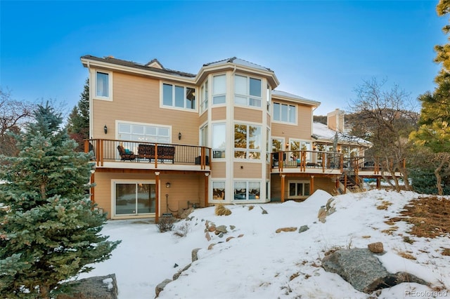 snow covered back of property with a wooden deck