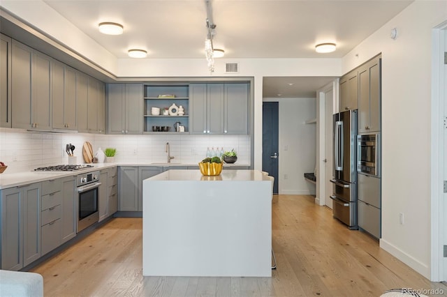 1750 Wewatta St Unit 809, Denver, CO 80202 - kitchen featuring appliances with stainless steel finishes, gray cabinets, open shelves, a sink, and tasteful backsplash
