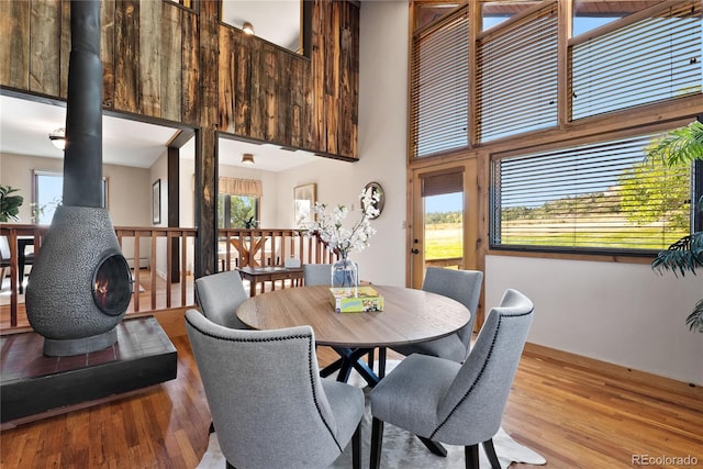 dining space with light wood-type flooring, a towering ceiling, and a wood stove