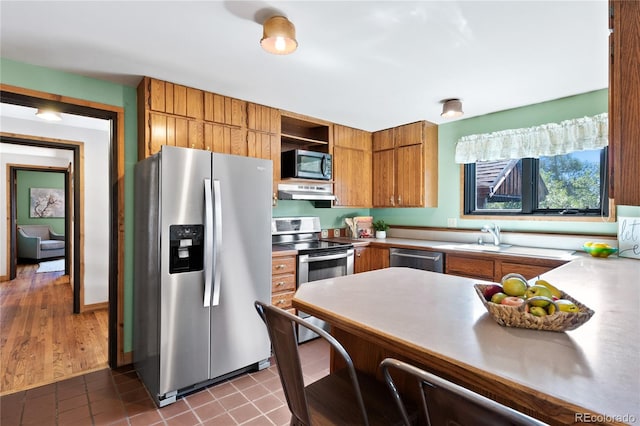 kitchen featuring exhaust hood, stainless steel appliances, light wood-type flooring, and sink