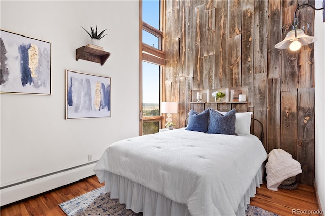 bedroom with a baseboard radiator and hardwood / wood-style floors