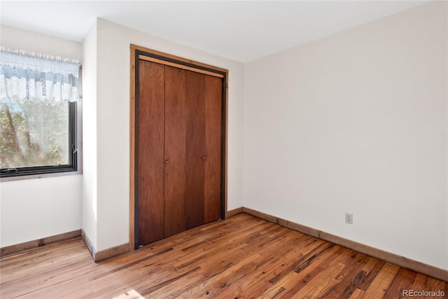 unfurnished bedroom featuring light hardwood / wood-style flooring and a closet