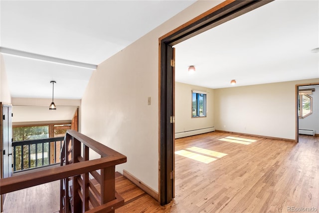 interior space with a baseboard heating unit, vaulted ceiling, and light hardwood / wood-style floors