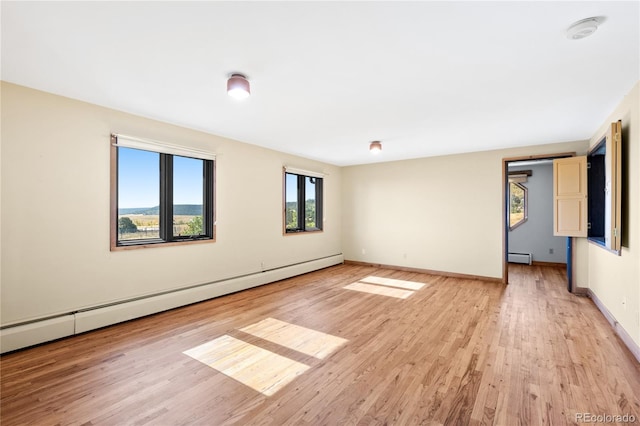 empty room with a baseboard radiator and light hardwood / wood-style floors