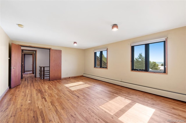 unfurnished room featuring light hardwood / wood-style floors and a baseboard radiator