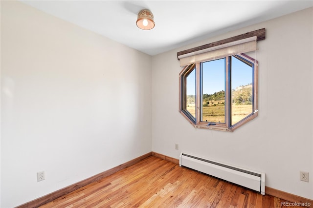 empty room with baseboard heating and light wood-type flooring