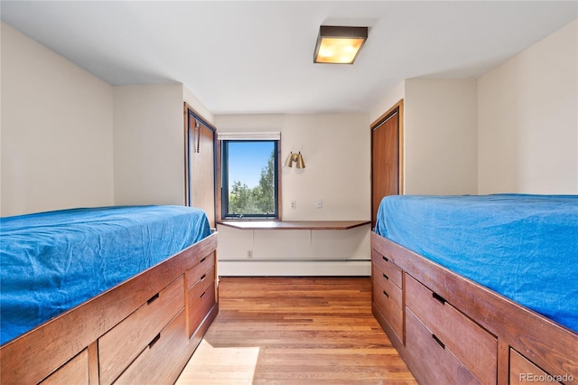 bedroom with a baseboard radiator and light hardwood / wood-style floors