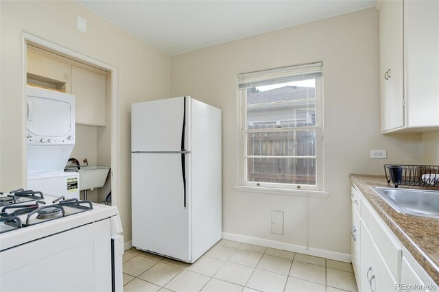 kitchen featuring sink, stacked washing maching and dryer, white appliances, and white cabinets