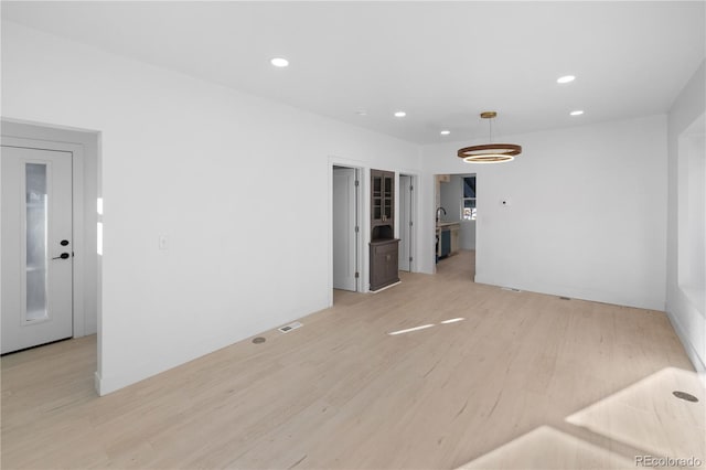 spare room featuring light hardwood / wood-style flooring and a notable chandelier