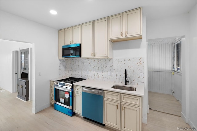 kitchen featuring tasteful backsplash, sink, cream cabinets, and appliances with stainless steel finishes