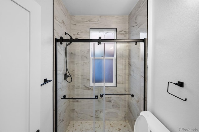 bathroom featuring toilet and a shower with shower door