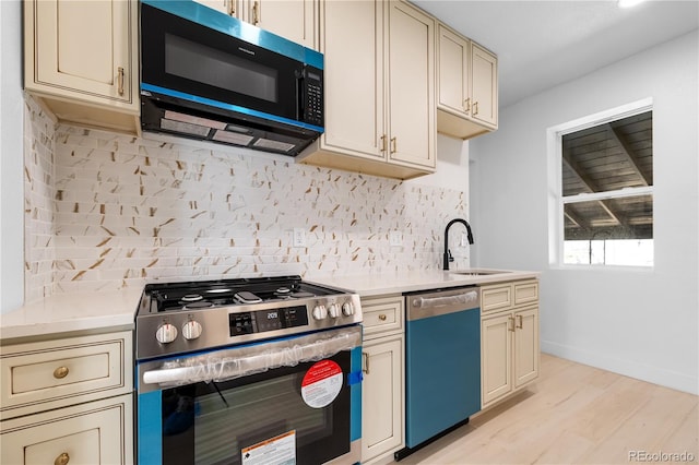 2207 E 25th, Denver, CO 80205 - kitchen with stainless steel range with gas cooktop, dishwasher, cream cabinetry, light wood-style floors, and light countertops