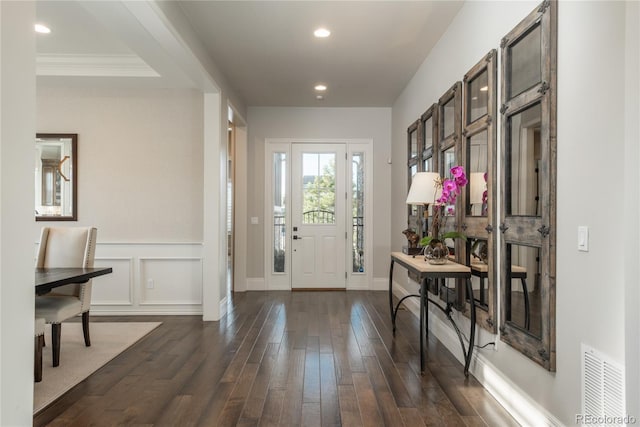 foyer entrance with crown molding and dark hardwood / wood-style flooring