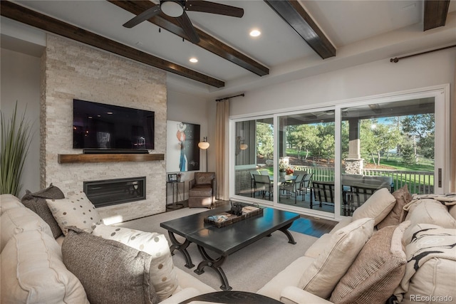 living room featuring beam ceiling, ceiling fan, and a fireplace