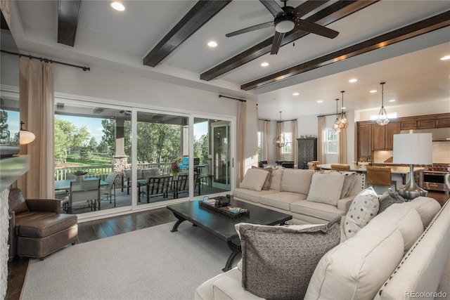 living room featuring ceiling fan with notable chandelier, beam ceiling, and hardwood / wood-style floors