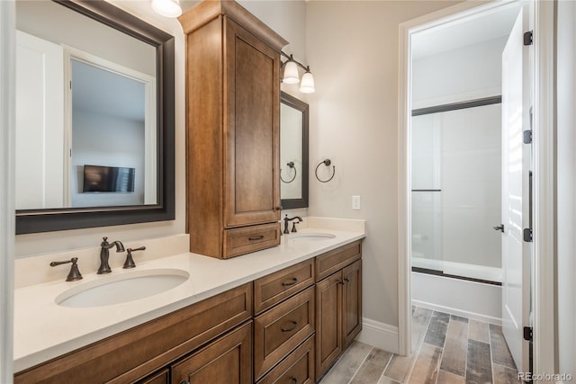 bathroom featuring vanity, wood-type flooring, and combined bath / shower with glass door