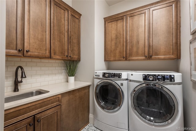 washroom with cabinets, washing machine and dryer, and sink