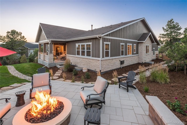 back house at dusk with a patio area and an outdoor fire pit