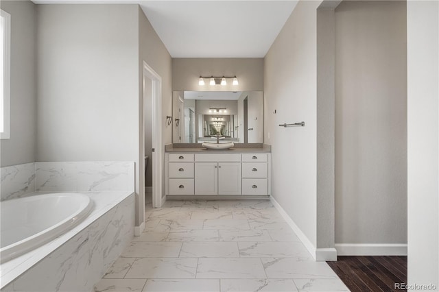 bathroom featuring vanity, baseboards, marble finish floor, and a garden tub