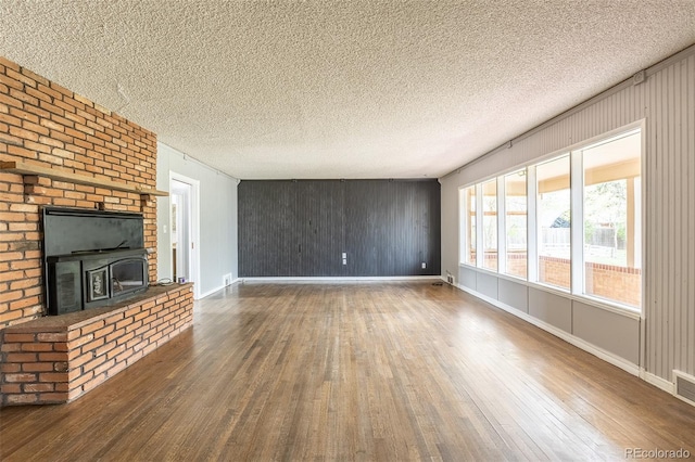 1345 Laredo St, Aurora, CO 80011 - unfurnished living room with baseboards, a fireplace, wood-type flooring, and a textured ceiling