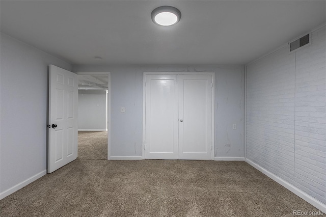 1345 Laredo St, Aurora, CO 80011 - unfurnished bedroom featuring a closet, brick wall, carpet floors, visible vents, and baseboards