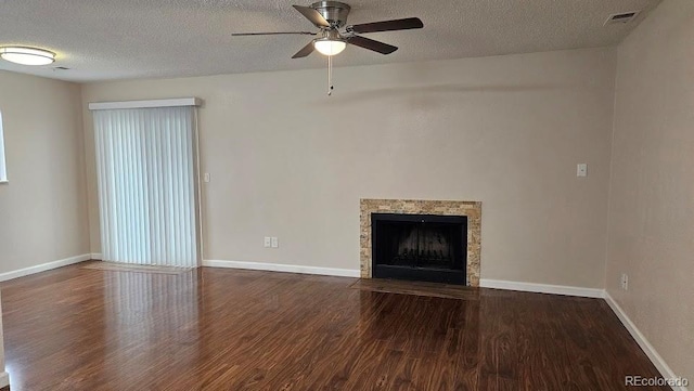 unfurnished living room with ceiling fan, a textured ceiling, baseboards, a fireplace with flush hearth, and wood finished floors