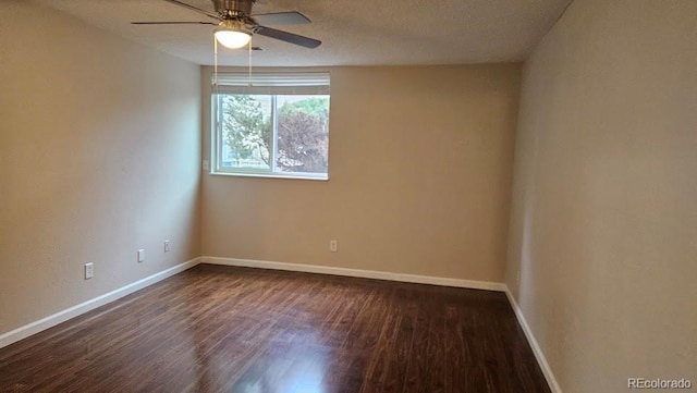 empty room featuring baseboards, dark wood finished floors, and ceiling fan