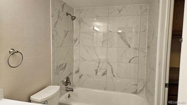 bathroom featuring toilet, a textured wall, and washtub / shower combination
