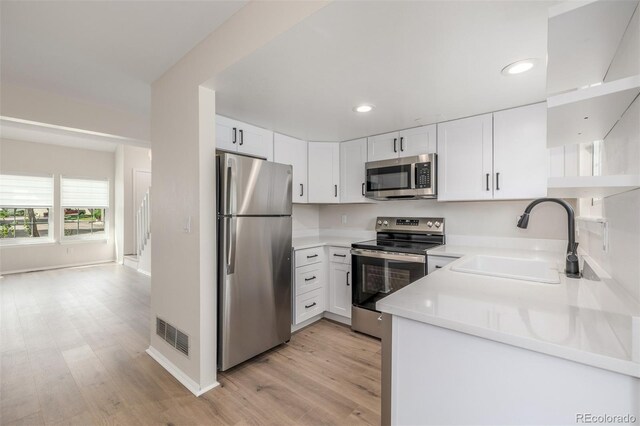 3912 S Richfield Way, Aurora, CO 80013 - kitchen with stainless steel appliances, a sink, light wood-style floors, recessed lighting, and white cabinetry