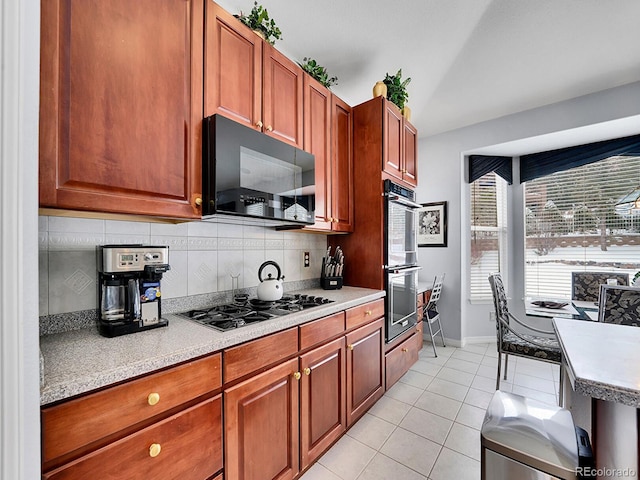 kitchen featuring light tile patterned floors, backsplash, and black appliances